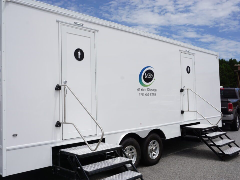 a white bathroom trailer that has two doors one for females and one for males